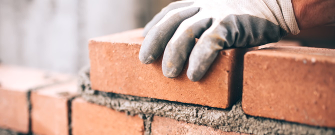 Close up of industrial bricklayer installing bricks on construction site