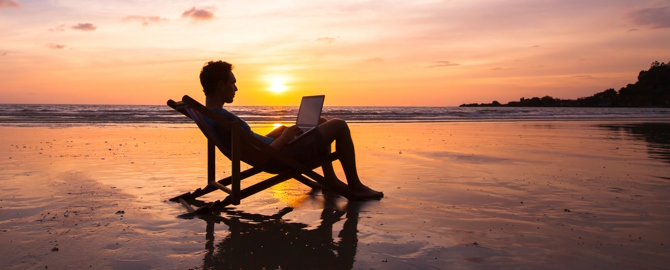 Business man with laptop working on the beach